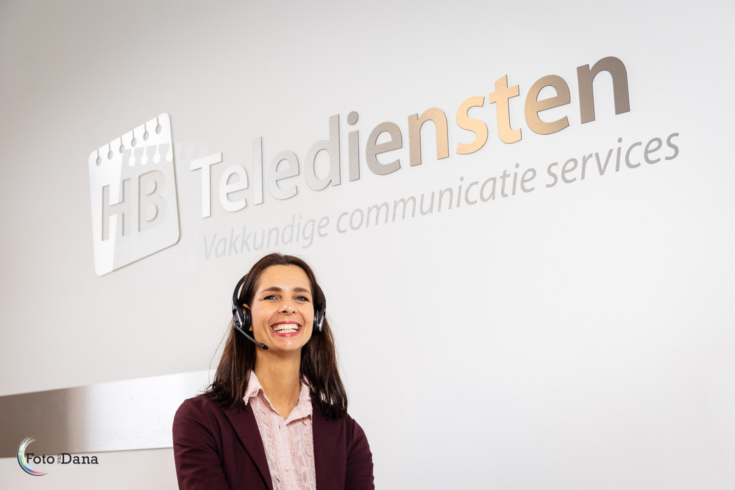 vrouw met handsfree onder logo van haar bedrijf